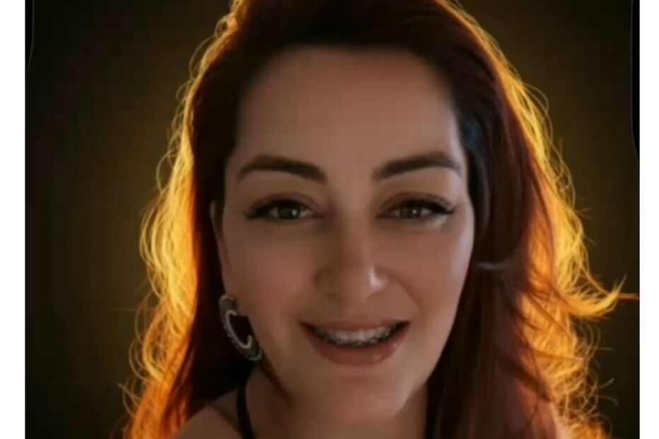 Mulher sorri com aparelho nos dentes e cabelo ruivo iluminado