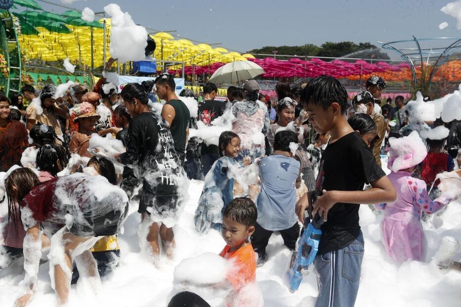 Pessoas celebram festival com espuma e guarda-sóis coloridos