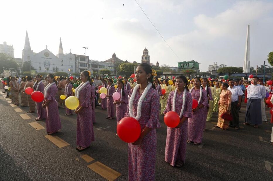 Pessoas reunidas numa rua com balões e vestes tradicionais