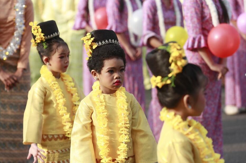 Crianças em trajes tradicionais participam num evento cultural