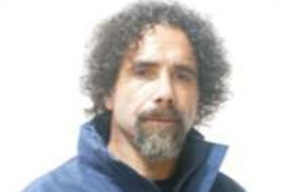 Homem com cabelo encaracolado e barba surge com casaco azul