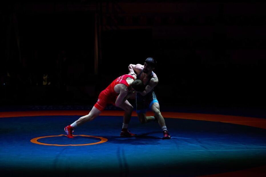 Dois lutadores competem num ringue azul e laranja