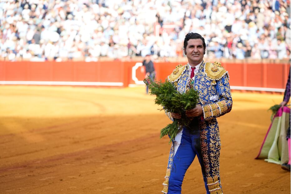 Um matador de toiros sorri com um ramo na mão na arena