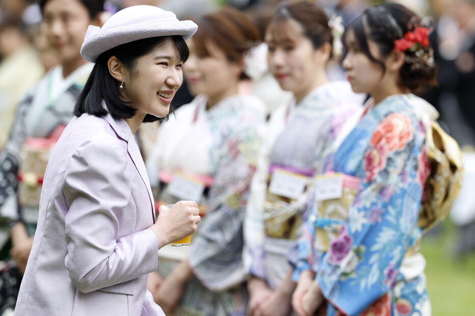 Mulheres vestem trajes tradicionais japoneses, com uma delas a segurar uma bebida