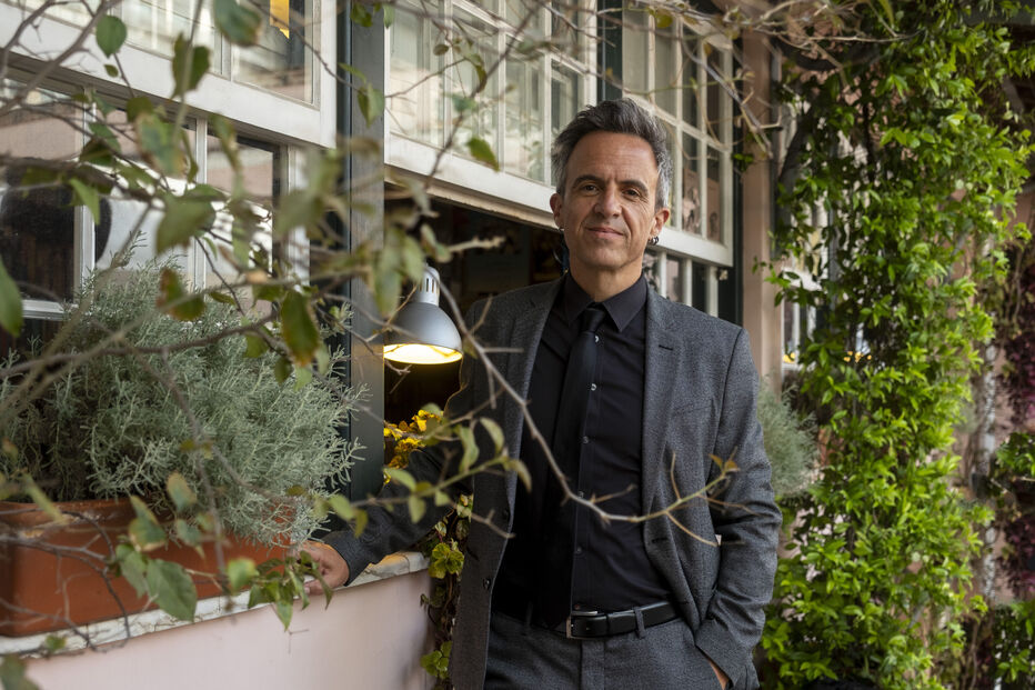 Homem posa junto a janela com plantas e iluminação suave