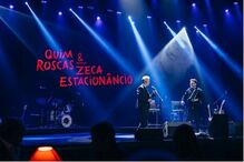 Concerto de Quim Roscas e Zeca Estacionâncio em palco com iluminação e banda