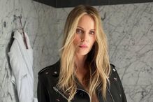 Charlize Theron posa com uma jaqueta de couro e calções num banheiro elegante