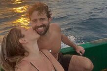 João Manzarra recebe beijo apaixonado de Catarina Camero num barco ao pôr do sol.
