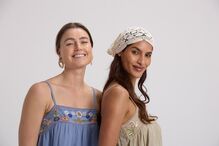 Mulheres sorrindo com vestidos bordados e touca de crochê