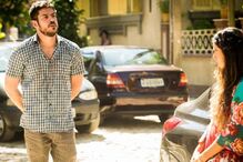 Homem e mulher junto a carros numa rua ensolarada