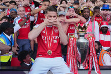 Fãs e jogadores do Arsenal celebram uma vitória com o troféu da Premier League