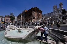 Pessoas refrescam-se numa fonte pública em Roma, Itália 