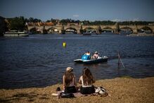 Pessoas sentadas nas margens do rio Vltava em Praga, República Checa