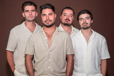 Quarteto de homens posa com camisas de manga curta e calças claras