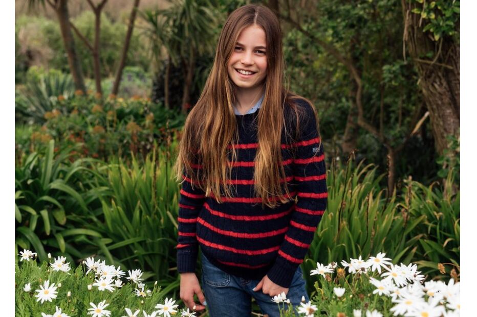 Princesa Charlotte, com 11 anos, sorri num campo florido