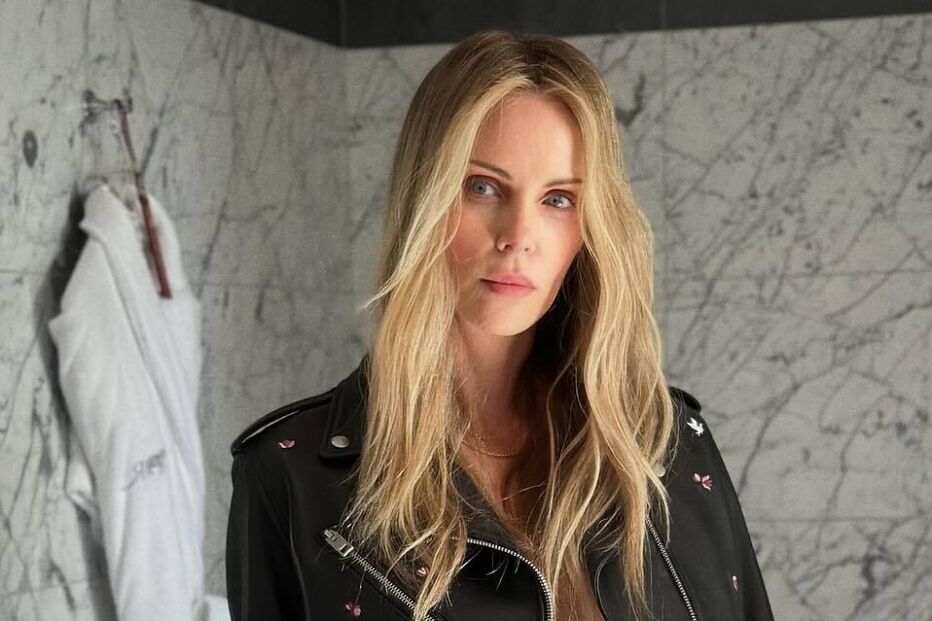 Charlize Theron posa com uma jaqueta de couro e calções num banheiro elegante