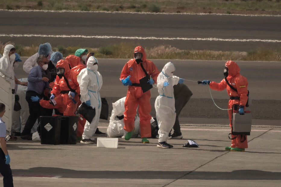 Os passageiros são pulverizados com desinfetante por funcionários do governo espanhol antes de embarcarem num avião, após desembarcarem do navio de cruzeiro MV Hondius, afetado pelo hantavírus, no aeroporto de Tenerife, nas Ilhas Canárias, Espanha, no domingo, 10 de maio de 2026.