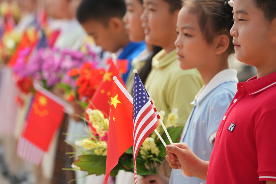Crianças com bandeiras dos EUA e China aguardam Trump na China