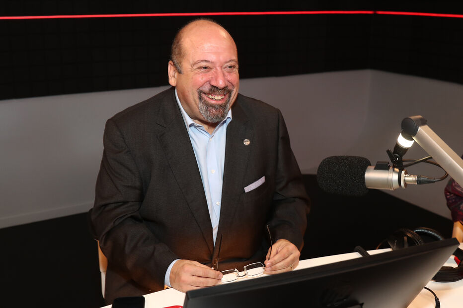 Locutor sorri num estúdio de rádio, pronto para partilhar as vozes que moldam a atualidade