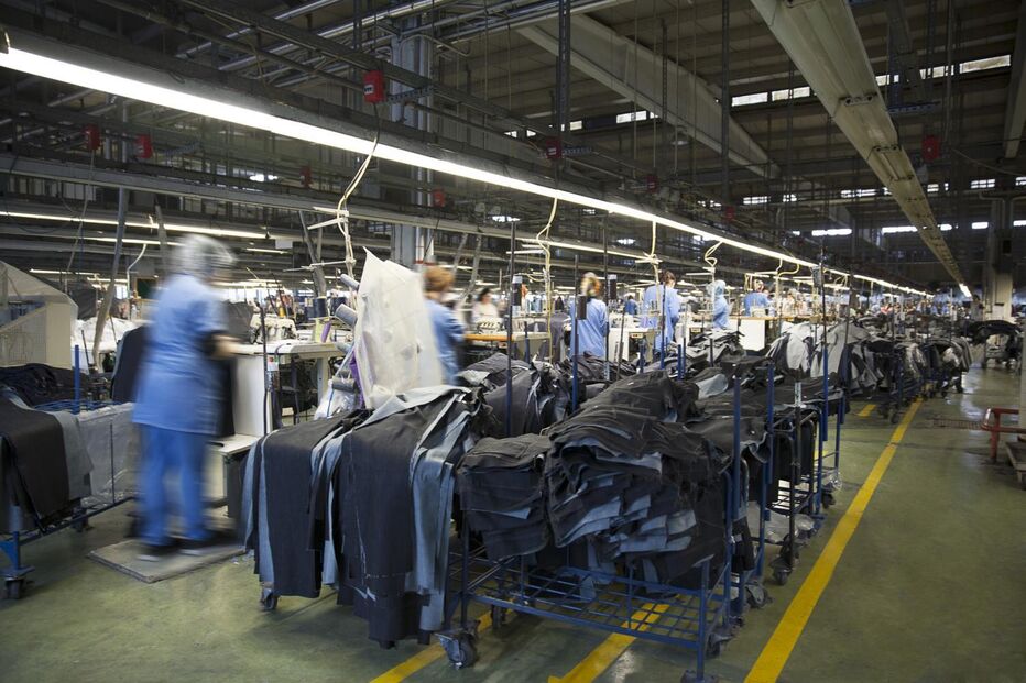 Numa fábrica, trabalhadores produzem peças de roupa em massa