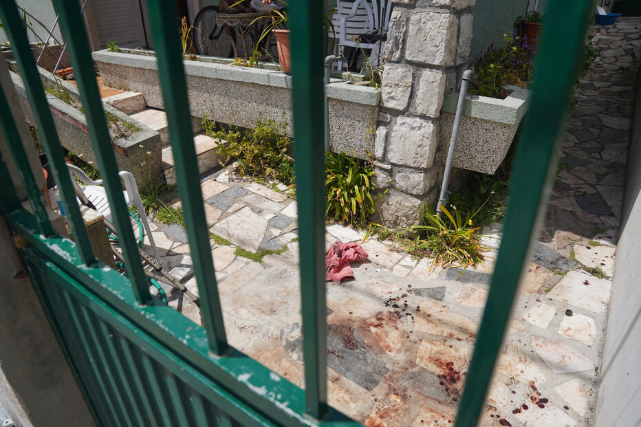 Sangue e um pano numa zona exterior, vistos através de uma cerca