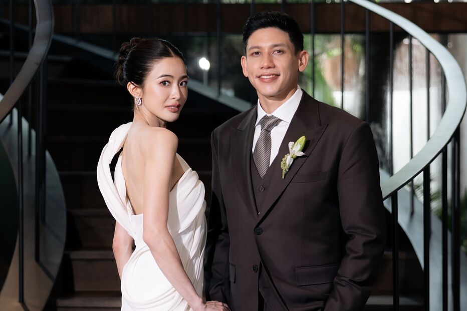 Casal posa para foto: noiva com vestido branco e noivo de fato