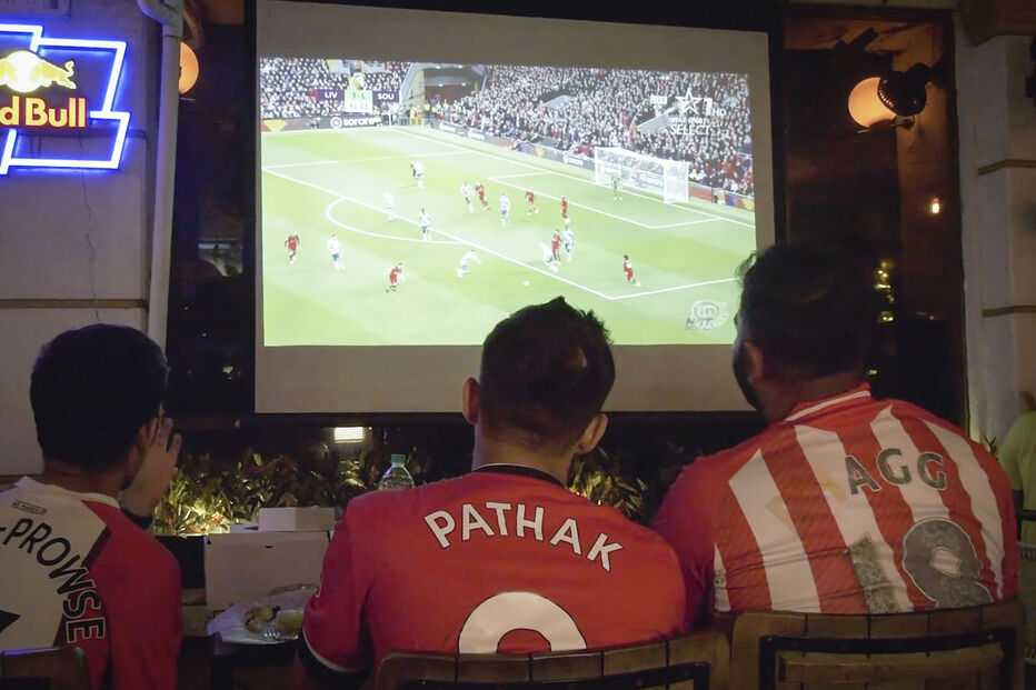Fãs de futebol assistem ao jogo Liverpool x Southampton num bar