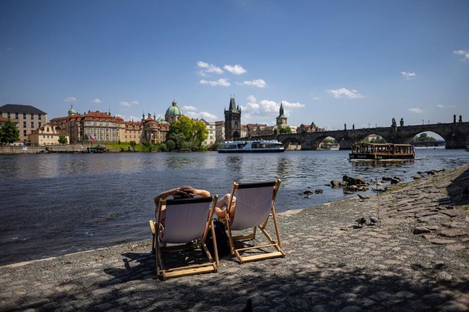 Pessoas sentadas nas margens do rio Vltava em Praga, República Checa