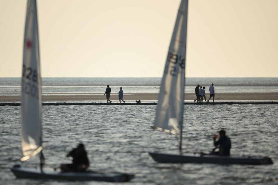 Pessoas caminham ao longo da marina em West Kirkby, Grã-Bretanha