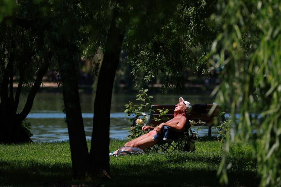 Homem a tomar banhos de sol no parque Titan em Bucareste, Roménia