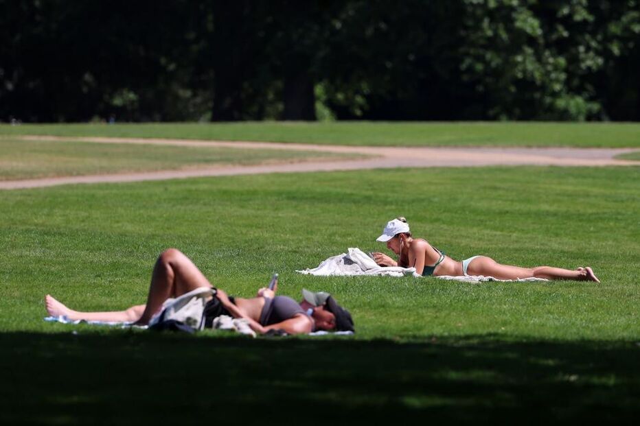 Pessoas a tomar banhos de sol num parque em Londres, Reino Unido 