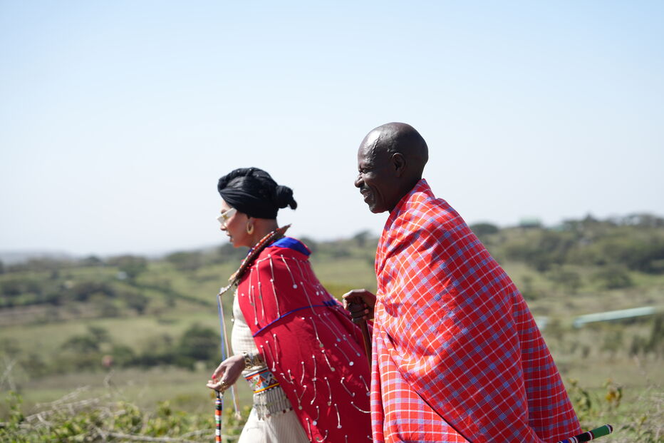 Homem e mulher Masai com vestes tradicionais caminham pela paisagem do Quénia