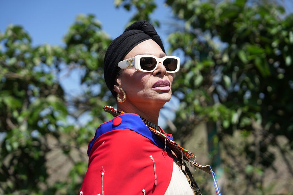 Mulher com turbante e óculos de sol posa com capa colorida e acessórios
