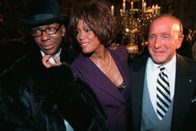 Bobby Brown, à esquerda, e Whitney Houston aparecem ao lado do produtor musical Clive Davis, à direita, numa festa pré-Grammy em Nova Iorque, a 24 de fevereiro de 1998.