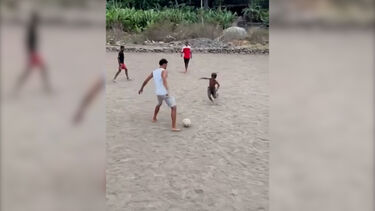 Vozinha descalço joga à bola com crianças num campo de terra batida em Cabo Verde