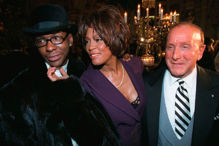 Bobby Brown, à esquerda, e Whitney Houston aparecem ao lado do produtor musical Clive Davis, à direita, numa festa pré-Grammy em Nova Iorque, a 24 de fevereiro de 1998.