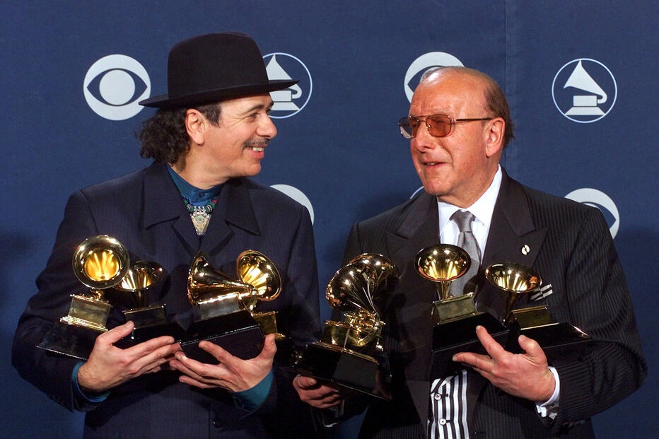 Carlos Santana, à esquerda, e o produtor Clive Davis posam com os seus prémios Grammy na 42.ª cerimónia dos Prémios Grammy, em Los Angeles, a 23 de fevereiro de 2000