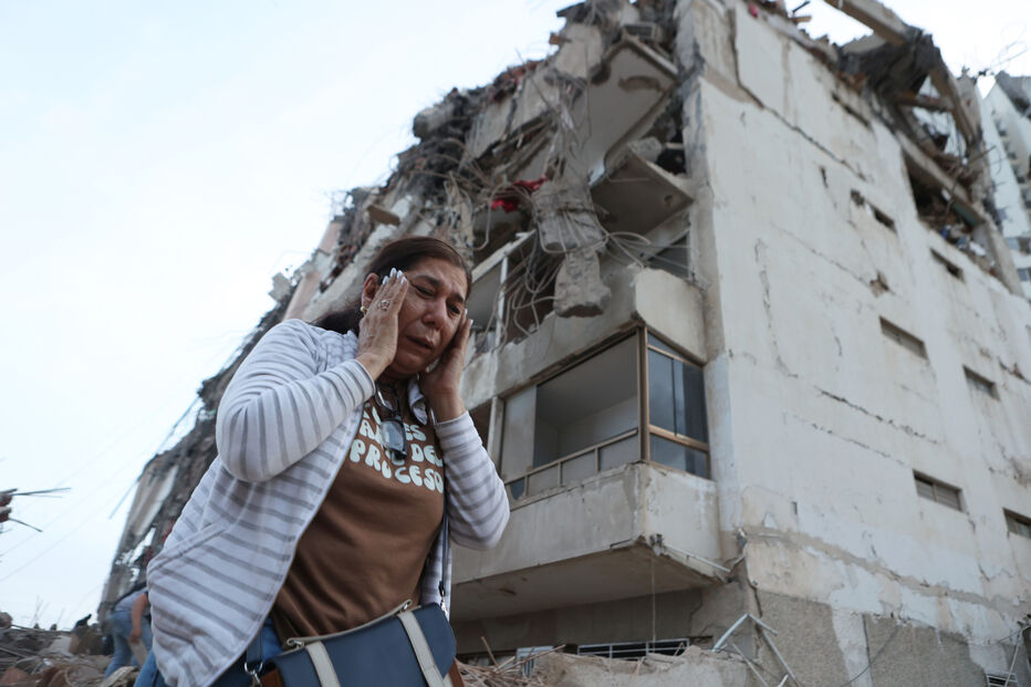 mulher passa por edifício danificado devido a sismos que abalaram a Venezuela