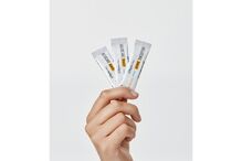 Mão segura 3 ampolas de Heliocare 360º Junior Oral Sticks