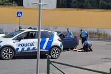 Polícia aborda homem no chão junto a carro da polícia, com caixas caídas