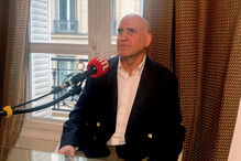 Um homem careca fala num microfone da RTL em Paris