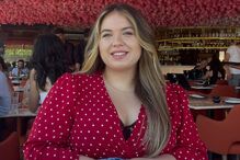 Mulher com blusa vermelha sentada sob flores rosadas