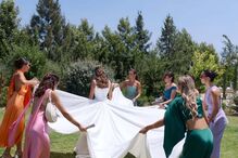 Noivas desdobram véu de noiva num jardim