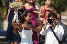 Noiva acena com o ramo enquanto fotógrafo regista o momento