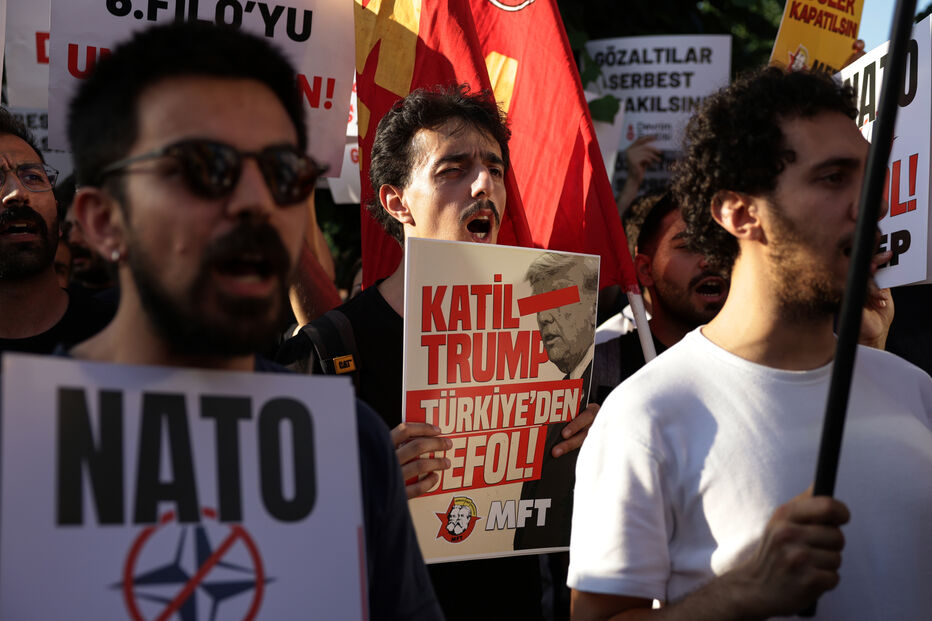 Pessoas marcham durante uma manifestação contra a cimeira da NATO, em Istambul, na Turquia, na terça-feira, 7 de julho de 2026. O cartaz no centro diz, em turco: «Trump, assassino. Sai da Turquia»