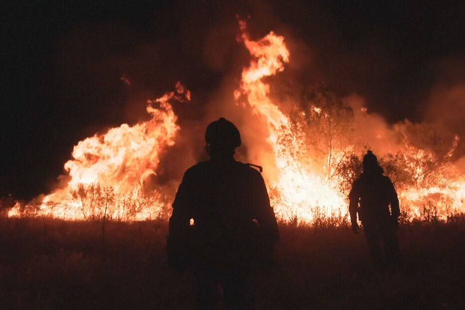 Dois bombeiros observam um incêndio florestal em Espanha