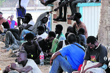 Migrantes em filas perto de uma barreira