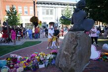 Homenagem a Dolly Parton em frente a uma estátua, com ofertas florais