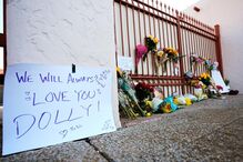 Um memorial com flores para Dolly Parton em frente a um portão com a mensagem 