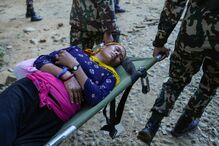 Membros de equipa de resgate transportam numa maca mulher que sobreviveu aos deslizamentos de terra no Nepal